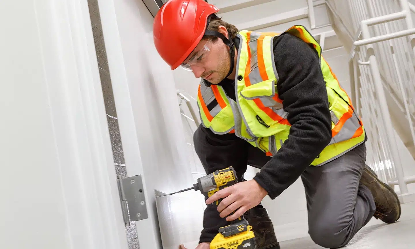WORRKS employee installing kick plate on stairwell door