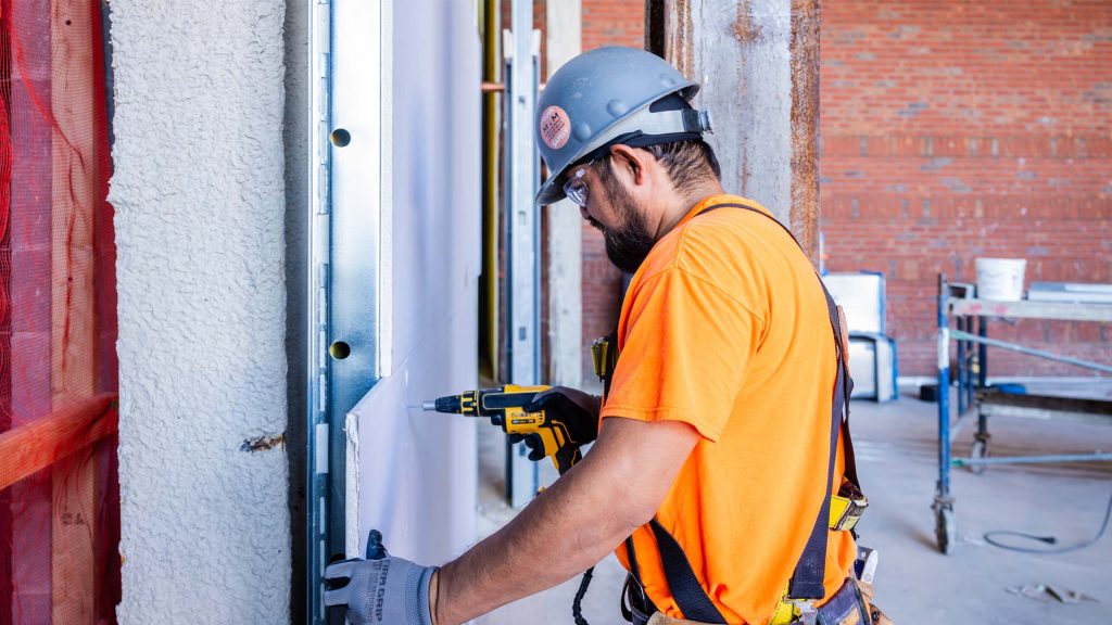 Man in safety gear installing dry wall panels