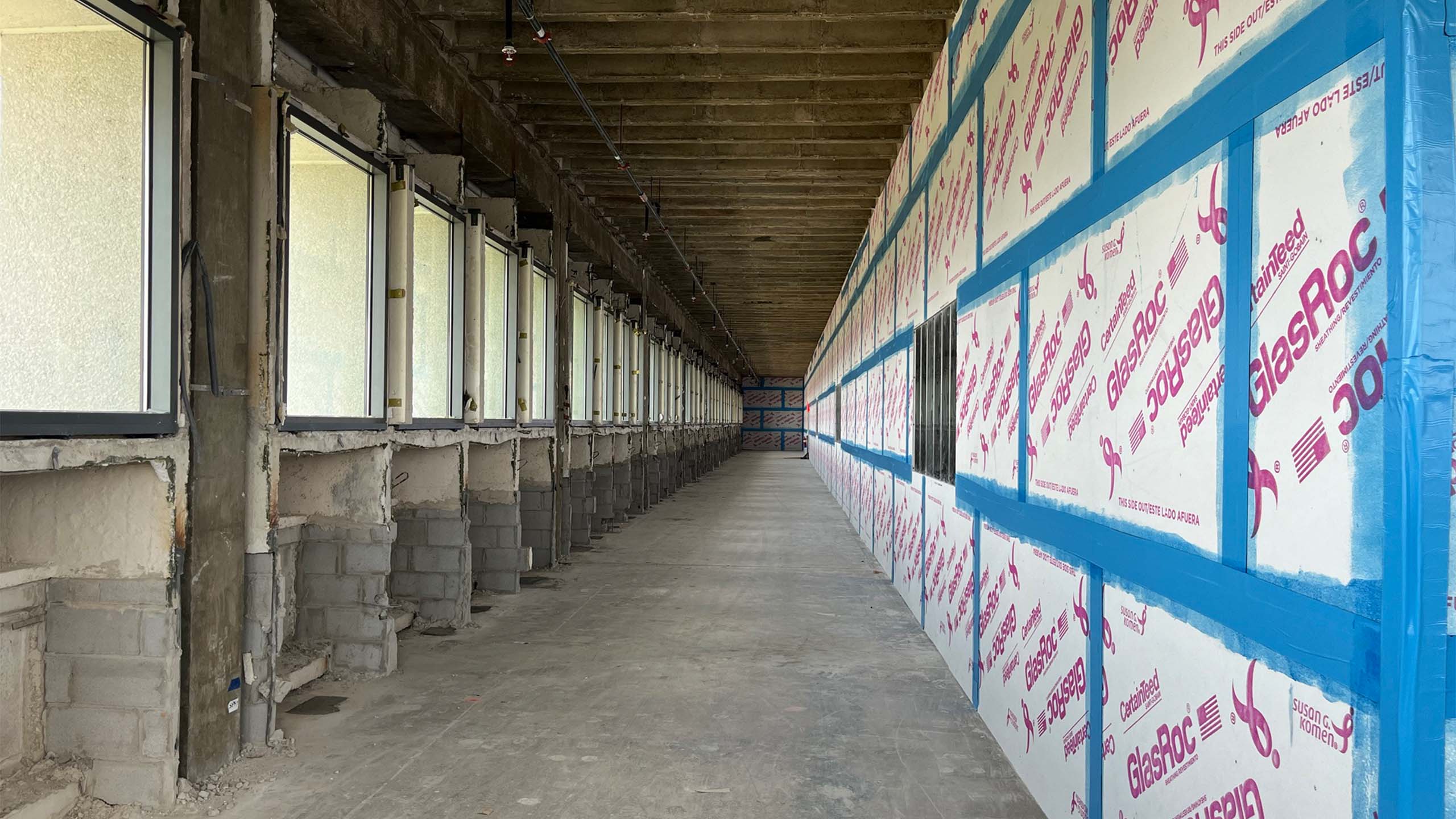 Unfinished hallway with drywall panels and exposed concrete